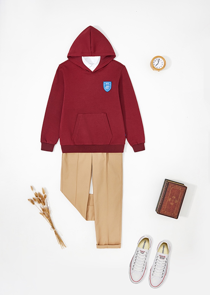Flat lay of a burgundy hoodie, chino trousers, white trainers, a book and a clock