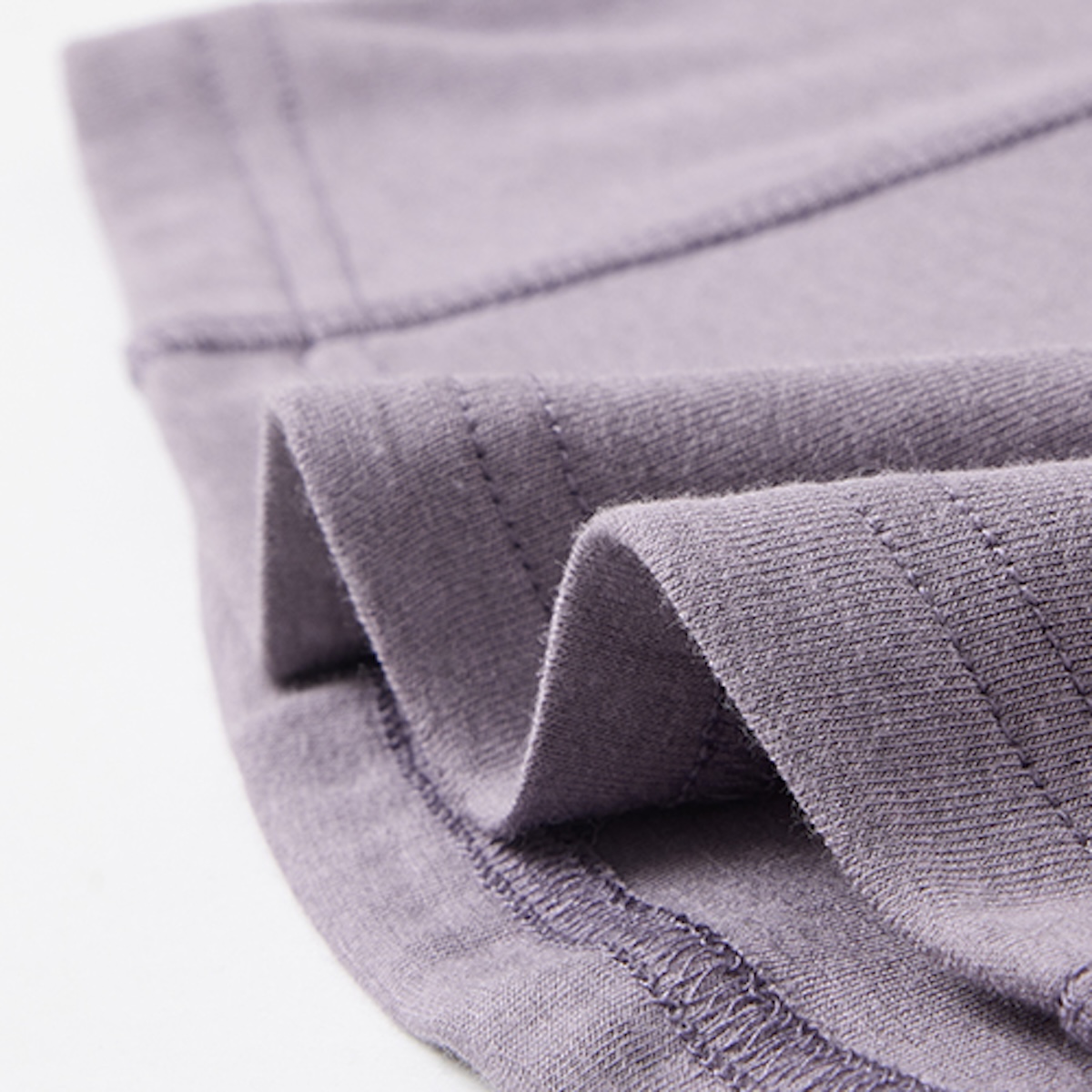 Macro of the double-needle stitched hem and side seam on a mauve cotton t-shirt