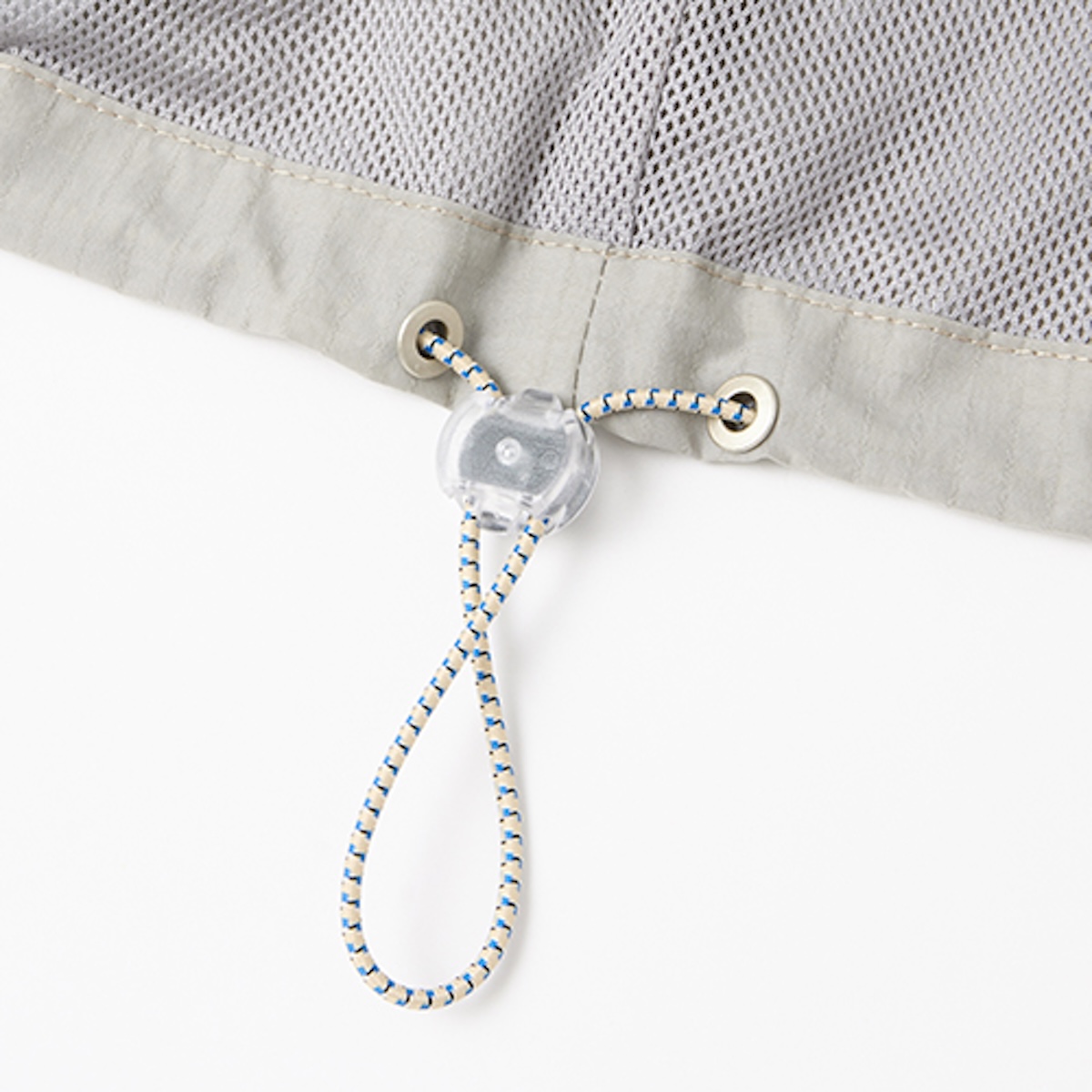 Macro of the mesh-lined hem, metal eyelets and clear cord lock on a windbreaker
