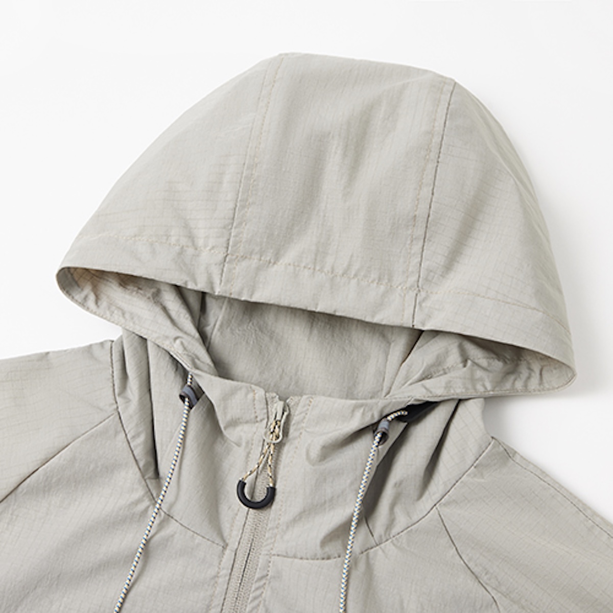 Hood and drawcord detail on a stone grey windbreaker, shot against white