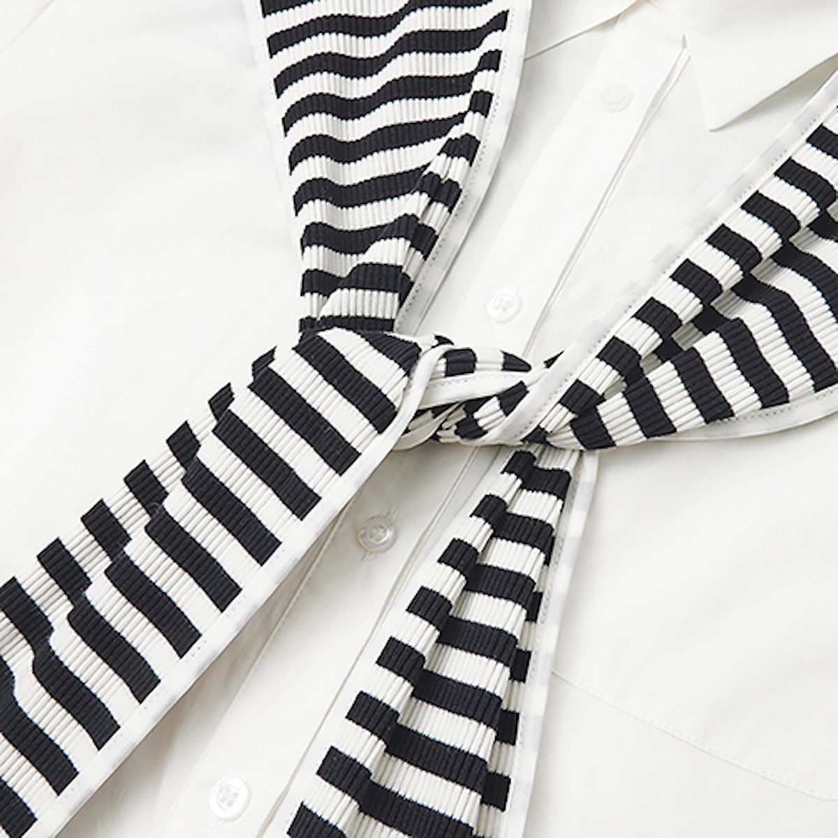 Close-up of the knotted striped rib-knit scarf against a white cotton shirt