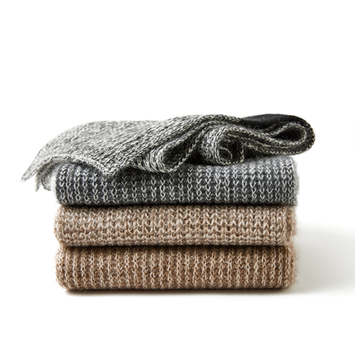 Four folded knitwear pieces stacked to show rib texture and yarn colour on white